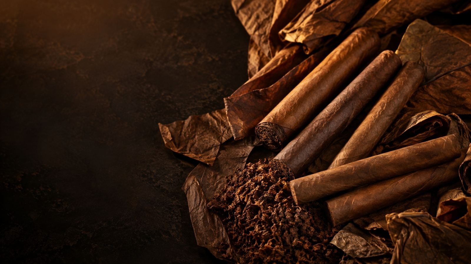 Finished cigars beside cured leaf